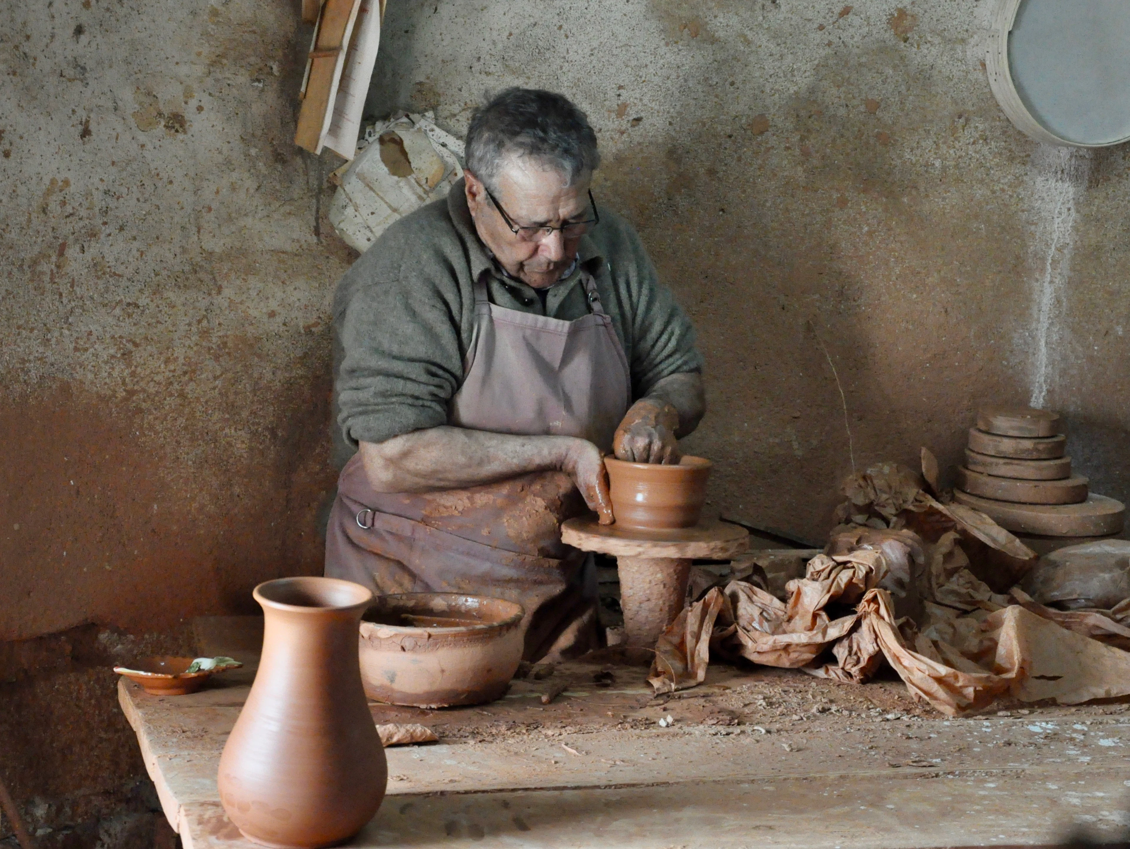 A potter shaping a clay pot on a wheel in a village workshop in Portugal
