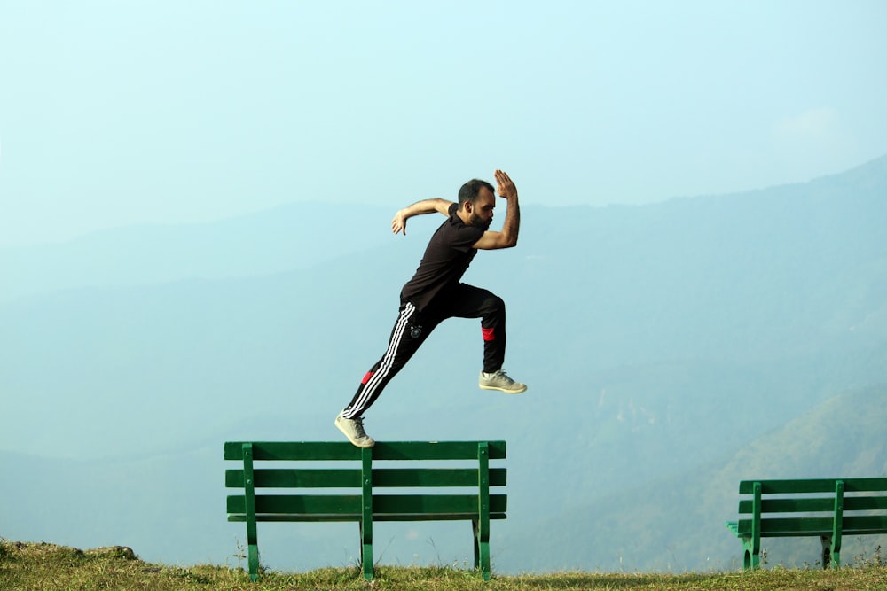 man jumping beside bench