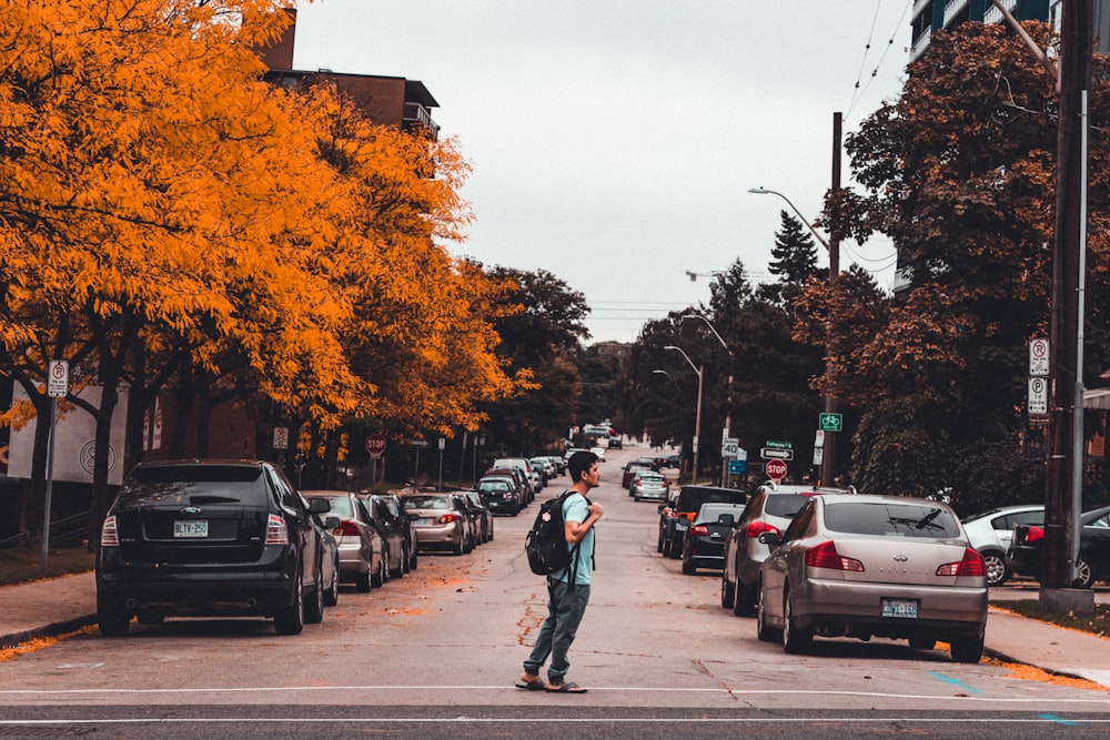 man wearing backpack in middle of road