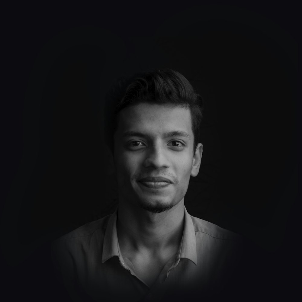 greyscale photo of smiling man wearing collared shirt