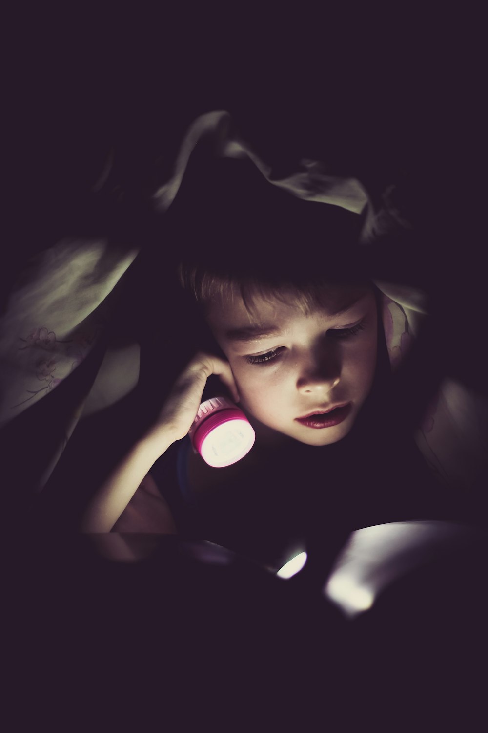 child holding flashlight reading book