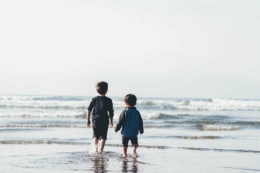 two boys walking on seashore