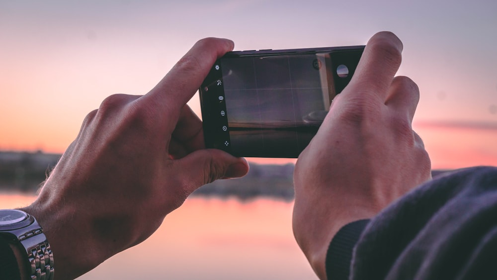 person holding a phone taking a picture of golden hour