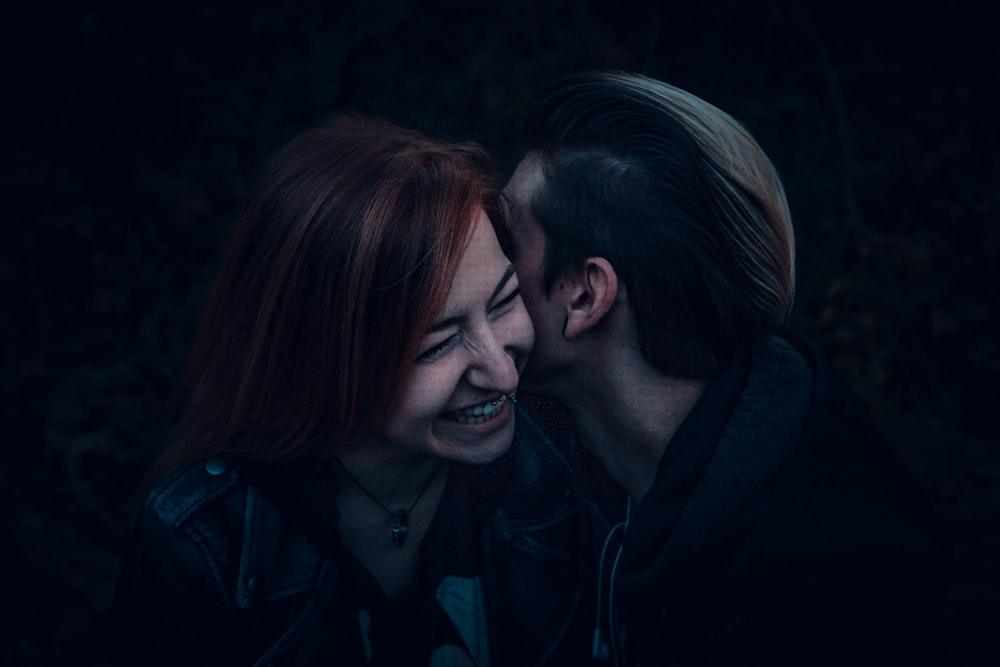 photography of two person whispering against black background