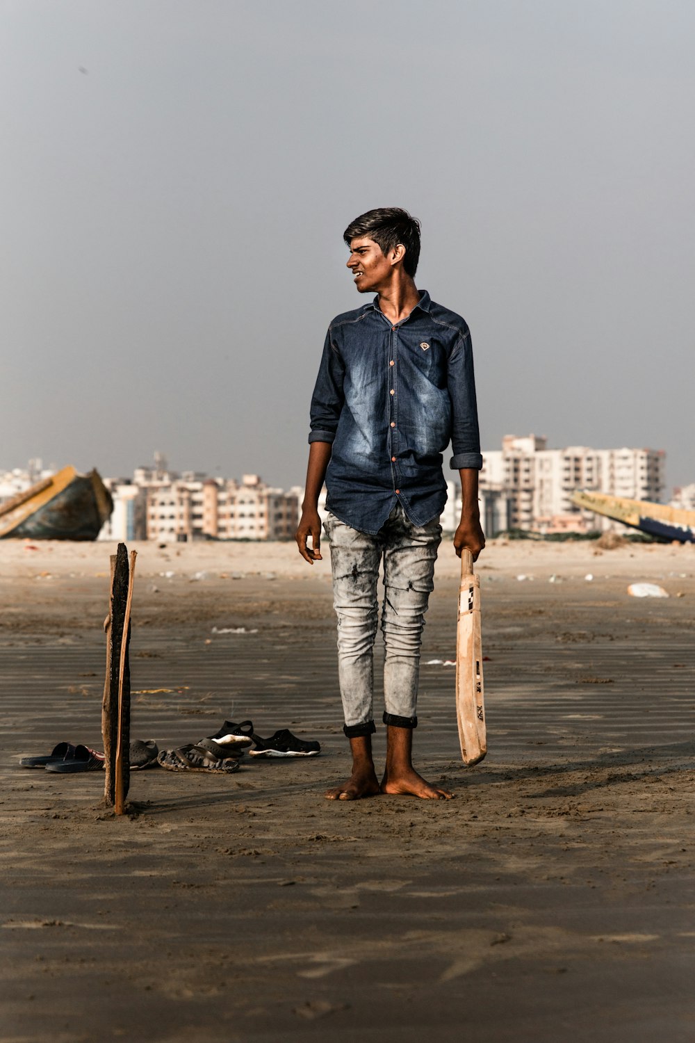 smiling man standing holding cricket bat while looking at right side during daytime