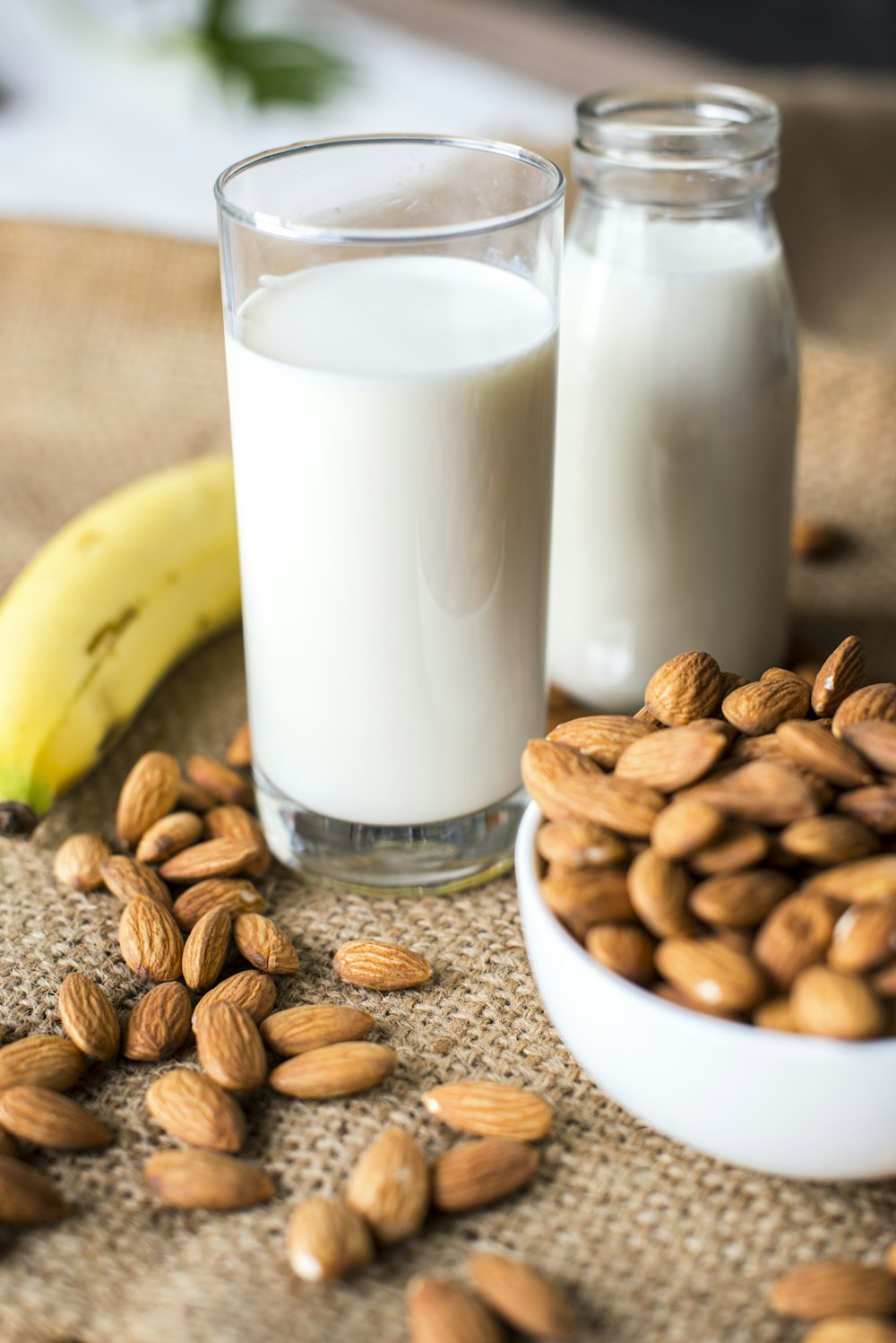 glass of milk beside bowl of nuts