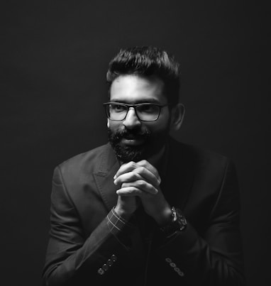 grayscale photography of sitting man wearing suit