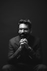 grayscale photography of sitting man wearing suit