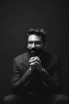 grayscale photography of sitting man wearing suit