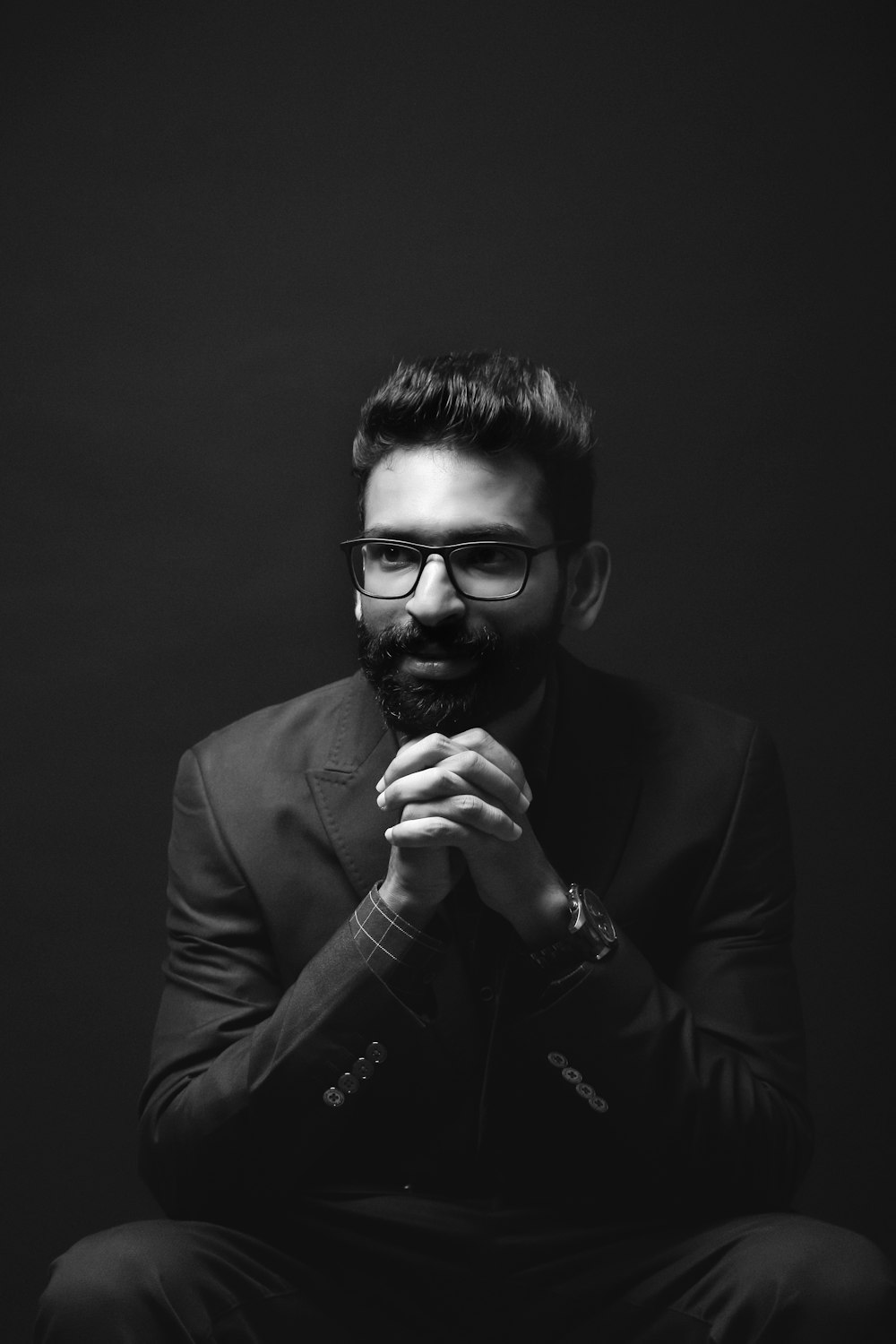 grayscale photography of sitting man wearing suit