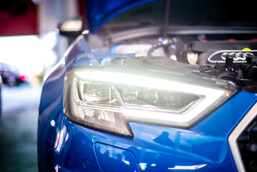 Close-up of a mechanic adjusting car headlights with precision tools.