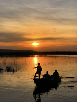 Happy family enjoying a day on a Fibralar boat in a calm lake at sunset.