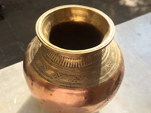 Close-up of a polished bronze pot catching warm kitchen light, highlighting its handcrafted texture