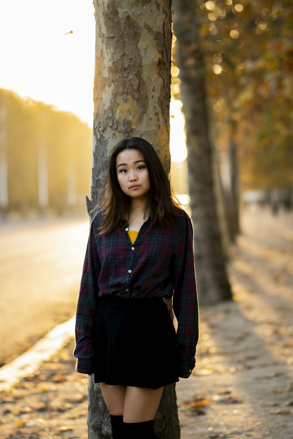 woman standing and posing next to a tree outdoor