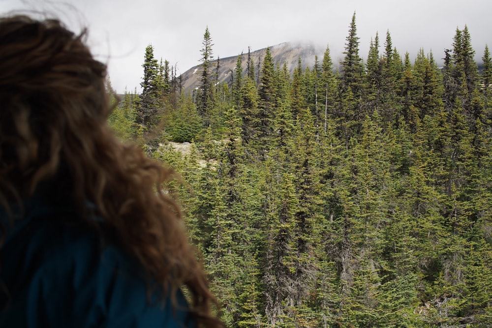 person in blue shirt in front of green leafed trees