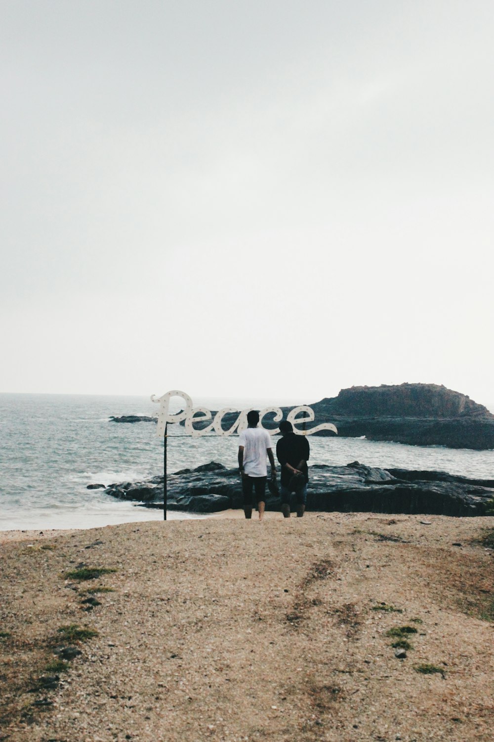 two persons standing on seashore