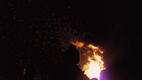 A candid shot capturing joyful faces of community members gathered around a warm bonfire at sunset.