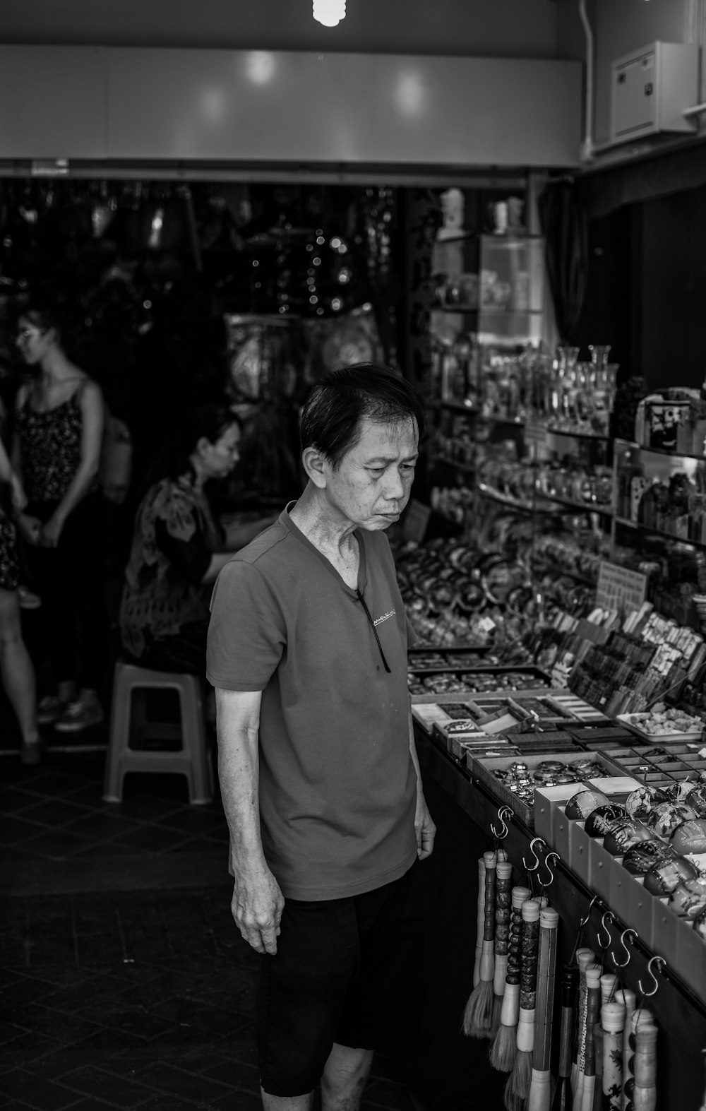 grayscale photo of man stand in front of stall