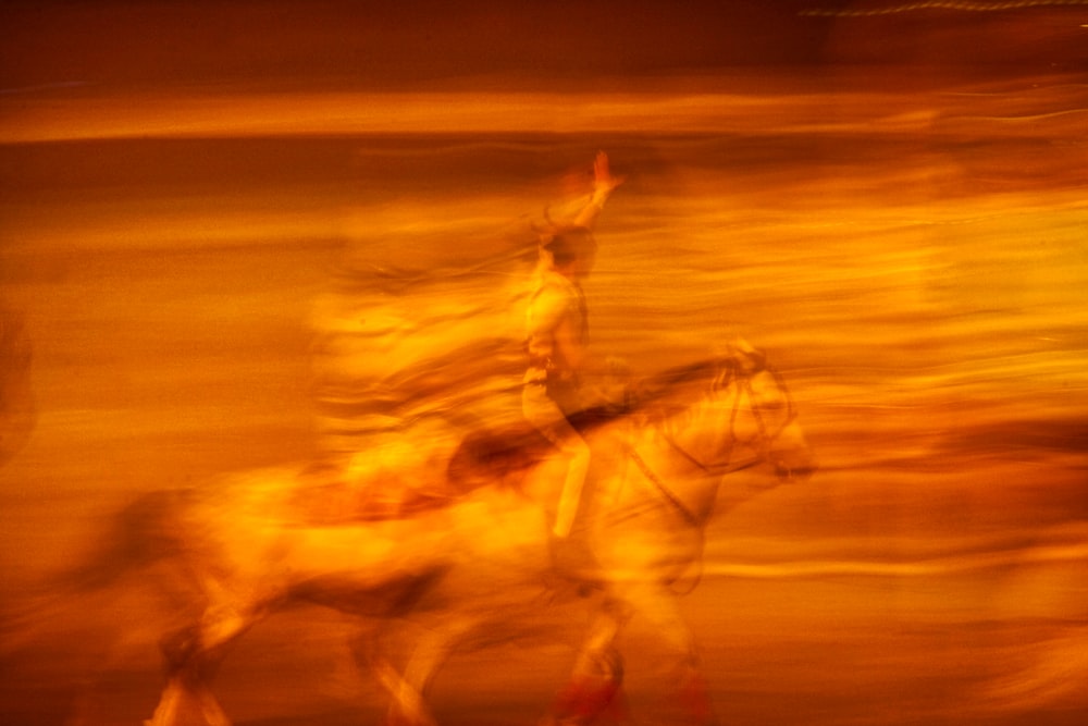 uma foto desfocada de um homem montado em um cavalo