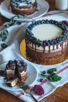 Close-up of a beautifully decorated chocolate cake with glossy ganache and fresh berries on a rustic wooden table