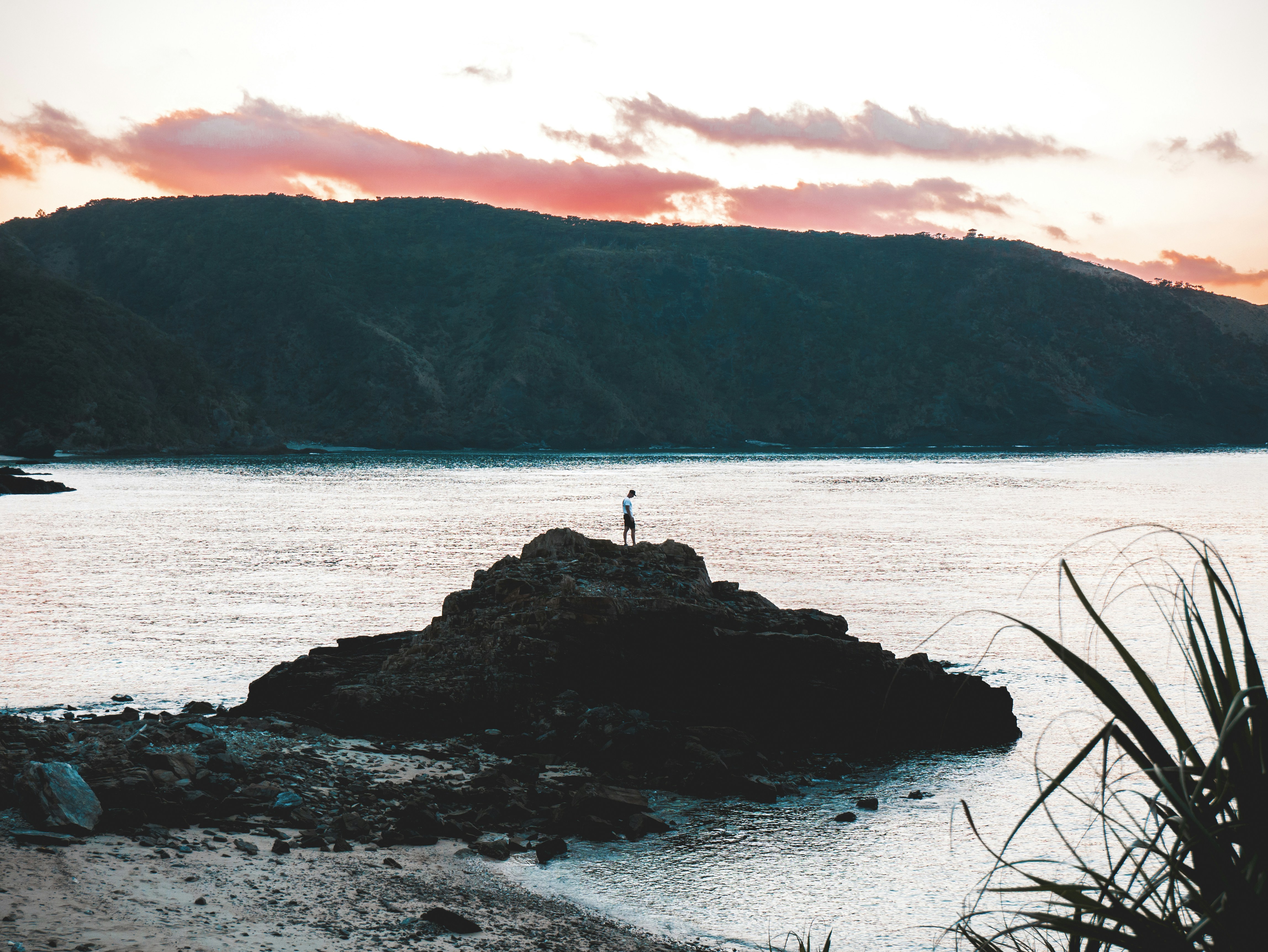 person standing on rock formation near body of water, 