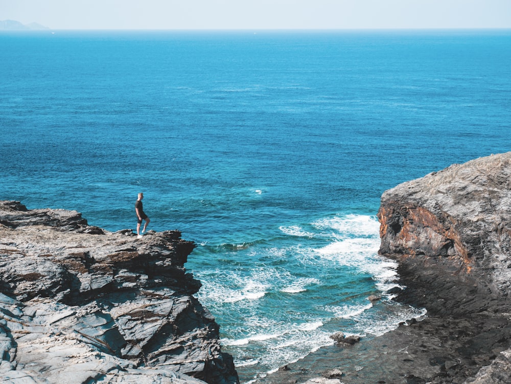 man standing on a rocky coast during daytime