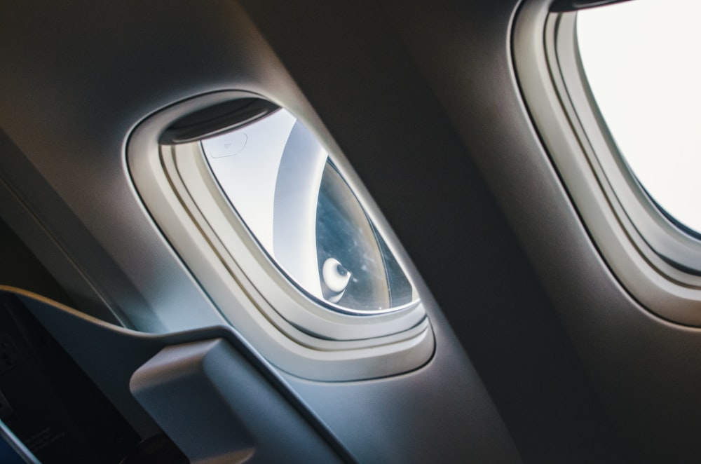 uma janela de avião com uma pessoa olhando pela janela