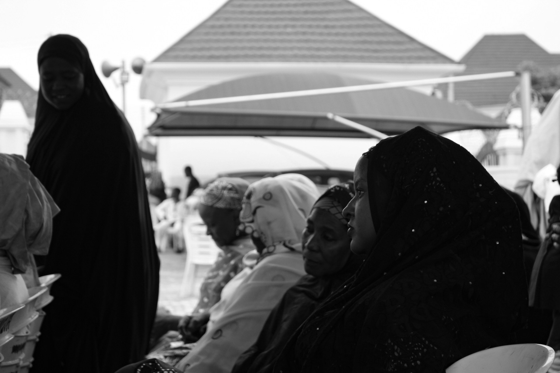 A candid moment capturing women in a remote village, their expressions a mix of strength and quiet determination.