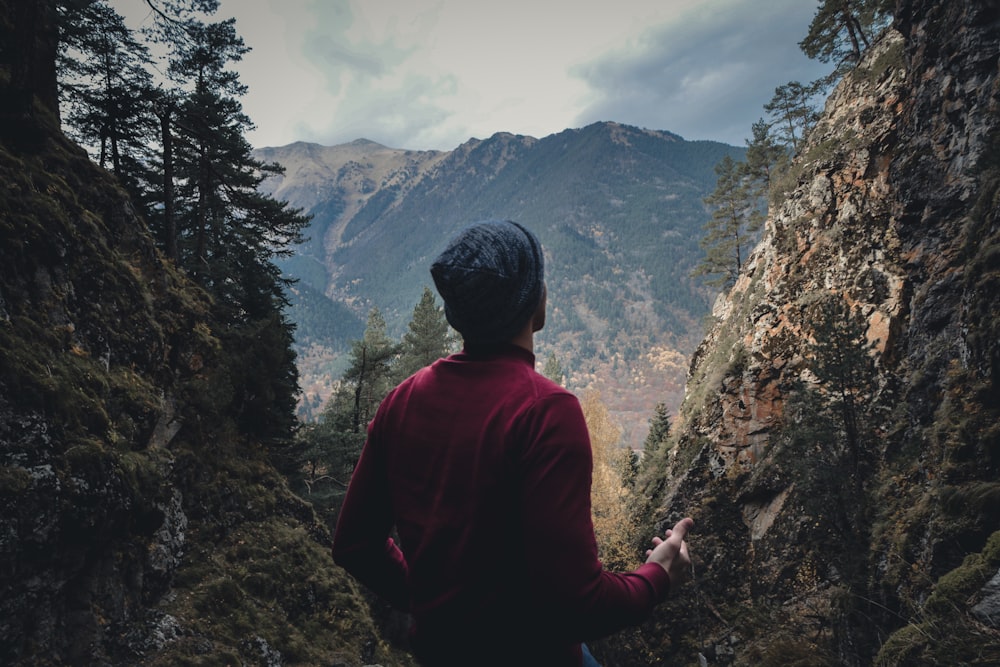 man in red sweater stands on top of hill