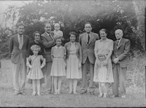 grayscale photo of family standing near trees
