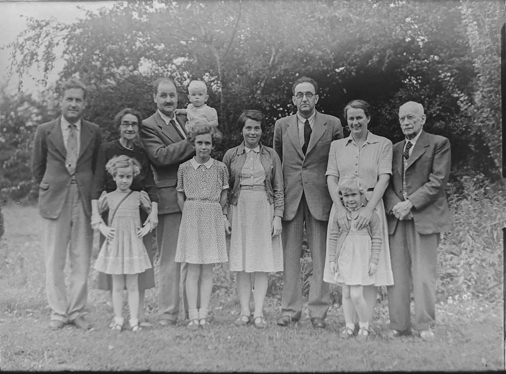 Foto en escala de grises de una familia de pie cerca de los árboles