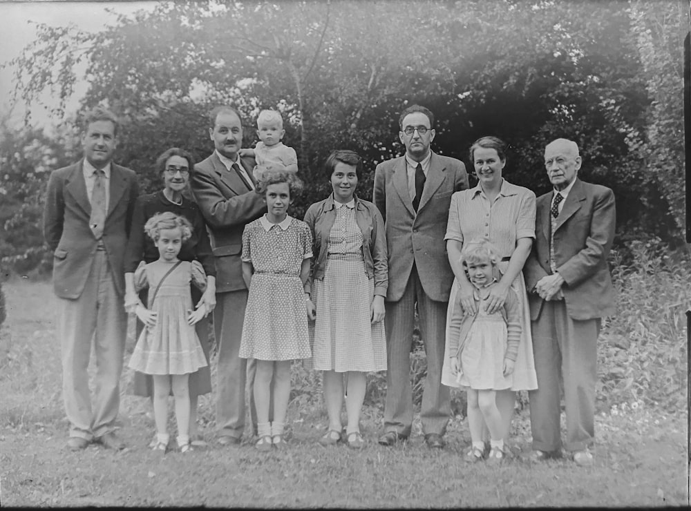 grayscale photo of family standing near trees