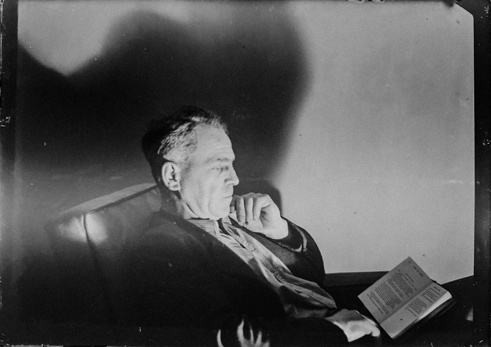 Graustufenfoto eines Mannes, der ein Buch liest