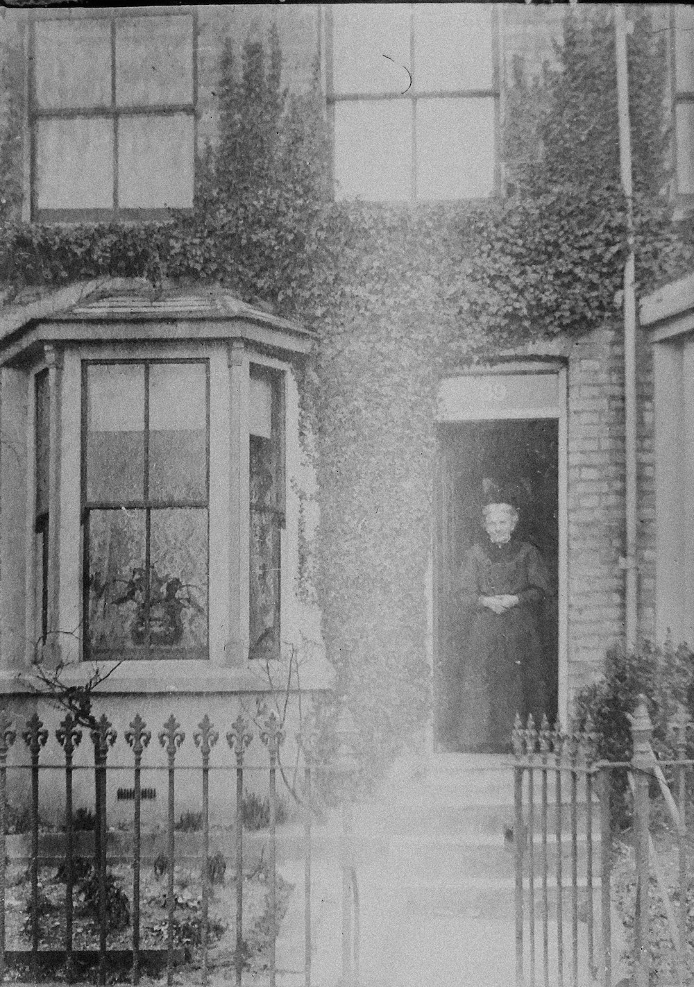 grayscale photo of 2 women standing in front of window