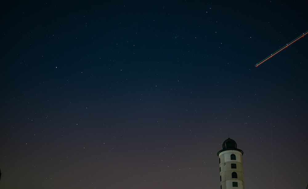 white and black lighthouse under starry sky