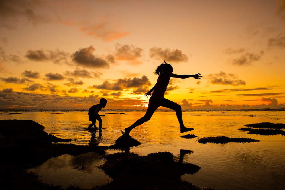 Silueta de niña y niño en la playa