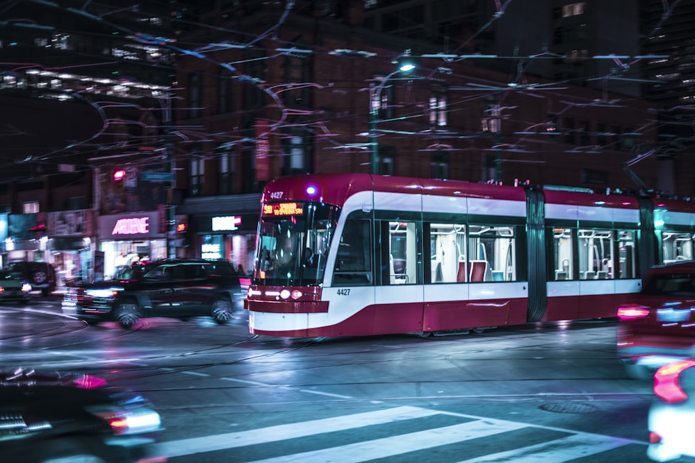 time lapse photo of red train passing by buildings during nighttime