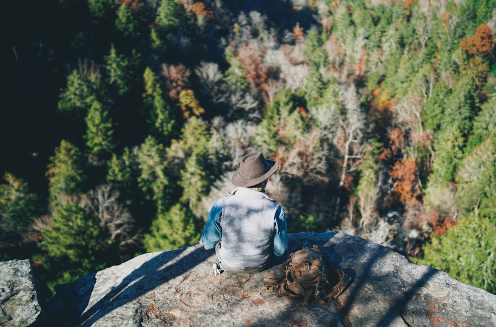 aerial view photography of man sitting on cliff during daytime