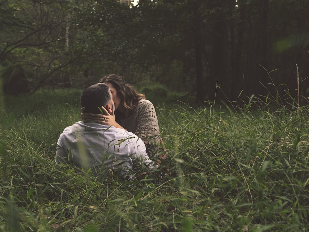 緑の芝生の上でキスをする男と女