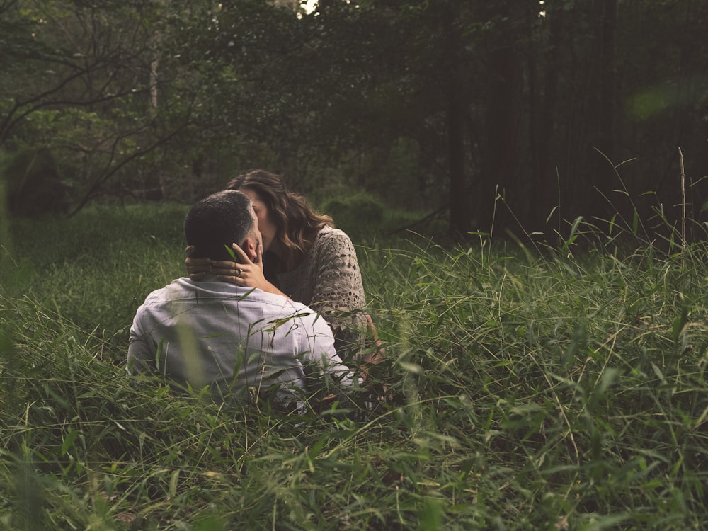 man and woman kissing on green grass field