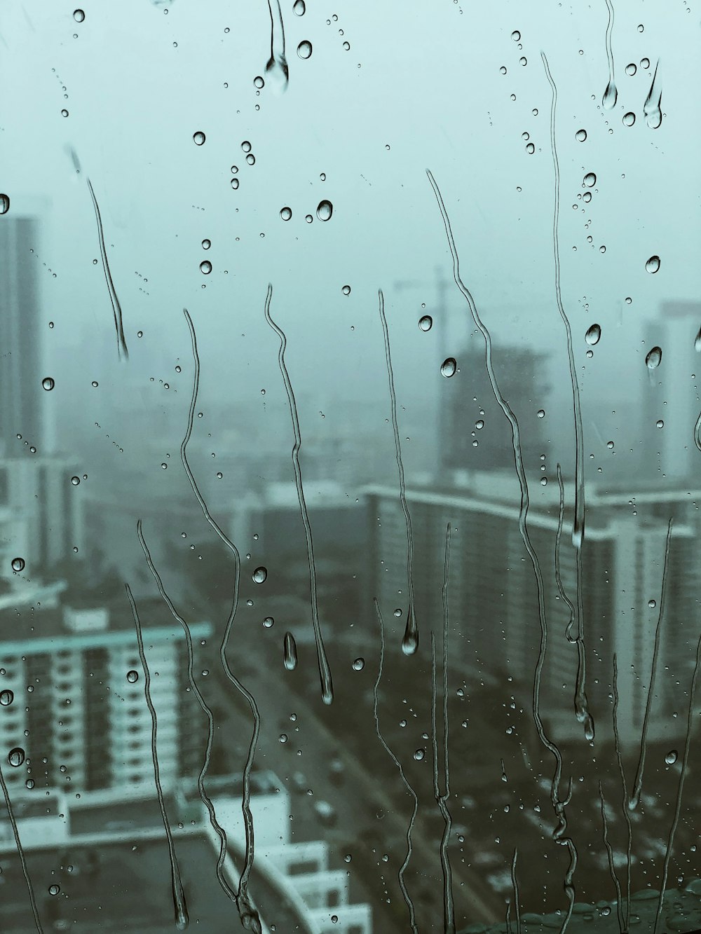 Vista da paisagem urbana a partir de vidro com gotículas de água