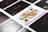 A close-up view of playing cards laid out in a grid pattern, with a prominent Queen of Spades card in the center. The other cards include assorted numbers and suits, all arranged neatly.