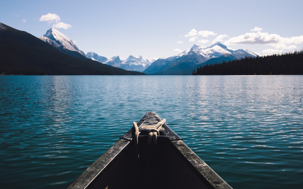 brown boat on calm sea beside mountain