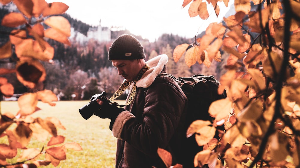 man wearing jacket holding DSLR camera during daytime