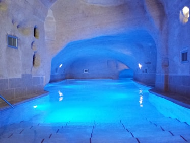 A serene spa pool surrounded by natural stone walls and soft candlelight ambiance.