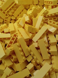 A pile of yellow plastic interlocking brick pieces, closely stacked together.