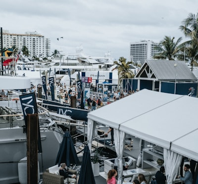 A vibrant seaside event with people gathered around boats and tents.