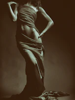 Sensual pose of a woman draped in sheer fabric, bathed in ambient evening light.