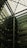 A modern architectural interior featuring a large atrium with a glass ceiling. The structure includes multiple floors of offices with glass windows. Some green, plant-covered walls add a touch of nature amidst the industrial design.