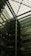 A modern architectural interior featuring a large atrium with a glass ceiling. The structure includes multiple floors of offices with glass windows. Some green, plant-covered walls add a touch of nature amidst the industrial design.